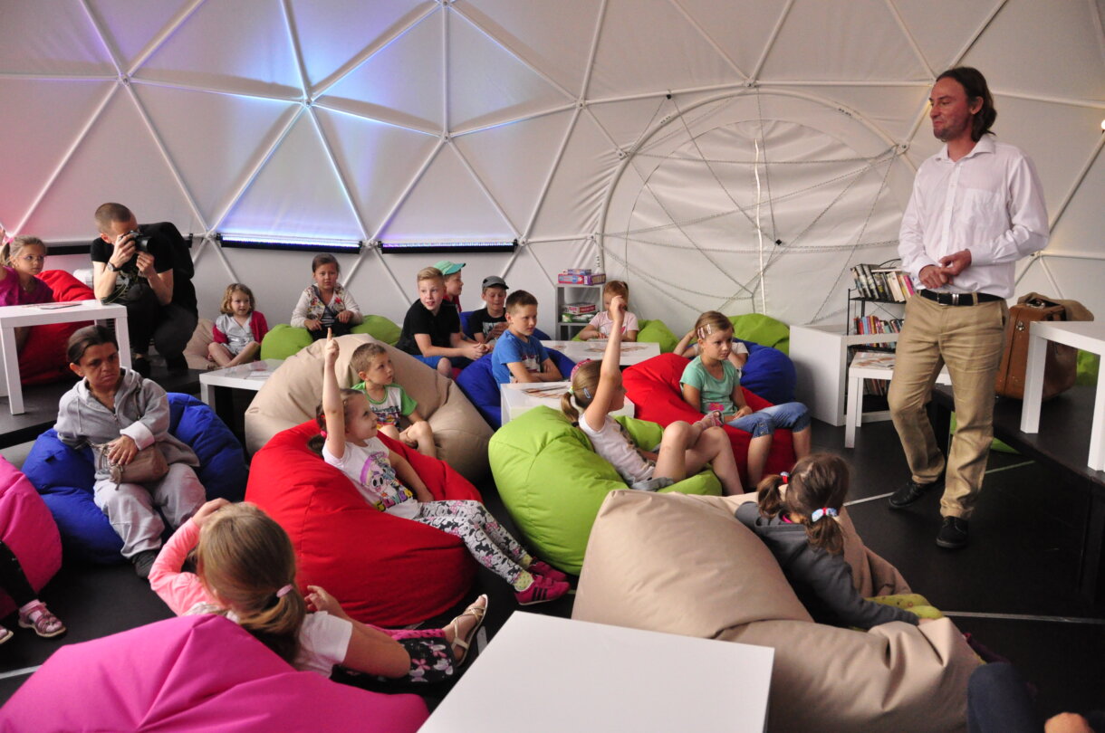 Dzieci siedzące na pufach w namiocie sferycznym