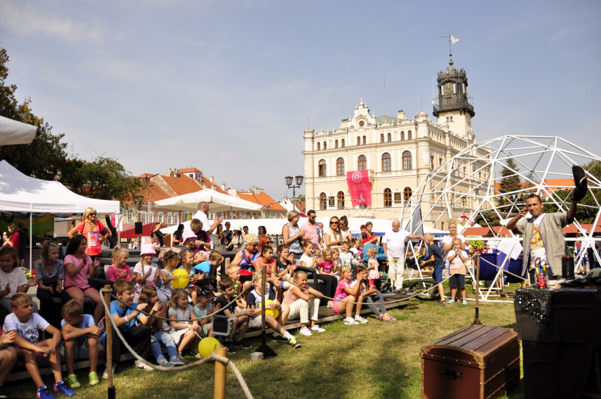 Dzieci siedzące na widowni, w tle ratusz