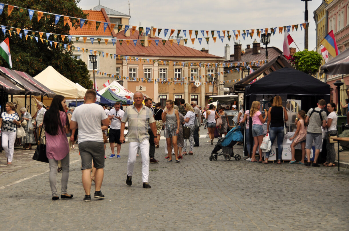 Ludzie chodzący wśród straganów, w tle ratusz