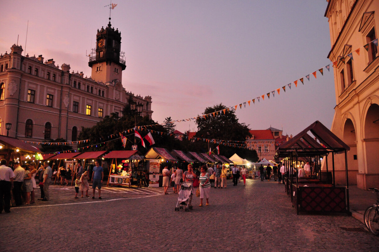 Ludzie chodzący wśród straganów, w tle ratusz