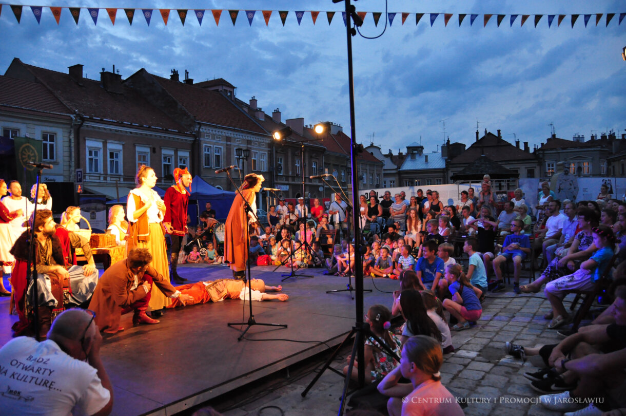 Grupa aktorów na scenie, w tle publiczność
