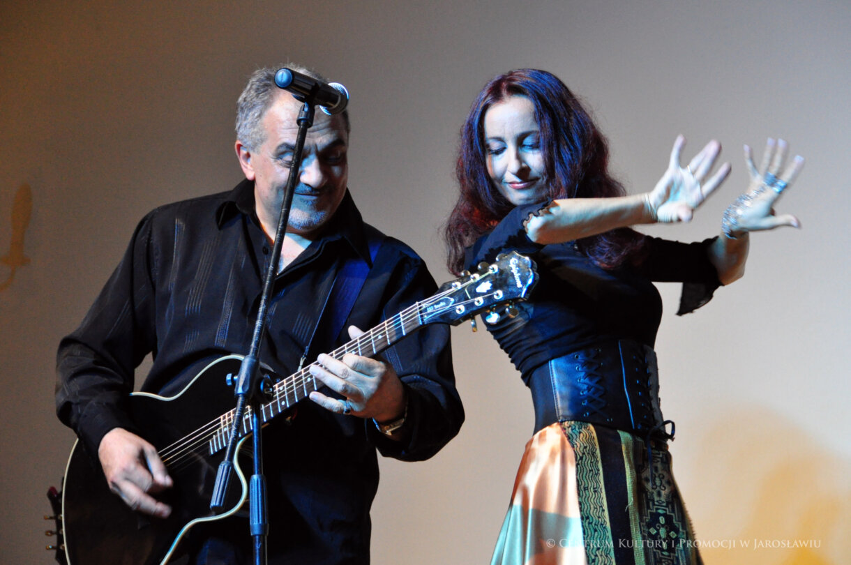 Mężczyzna grający na gitarze i tańcząca kobieta