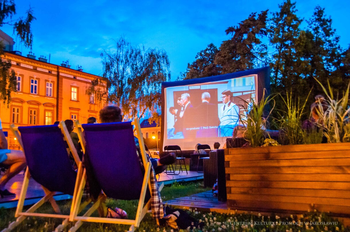 od tyłu widzowie na leżakach, w tle ekran Kino pod Gwiazdami