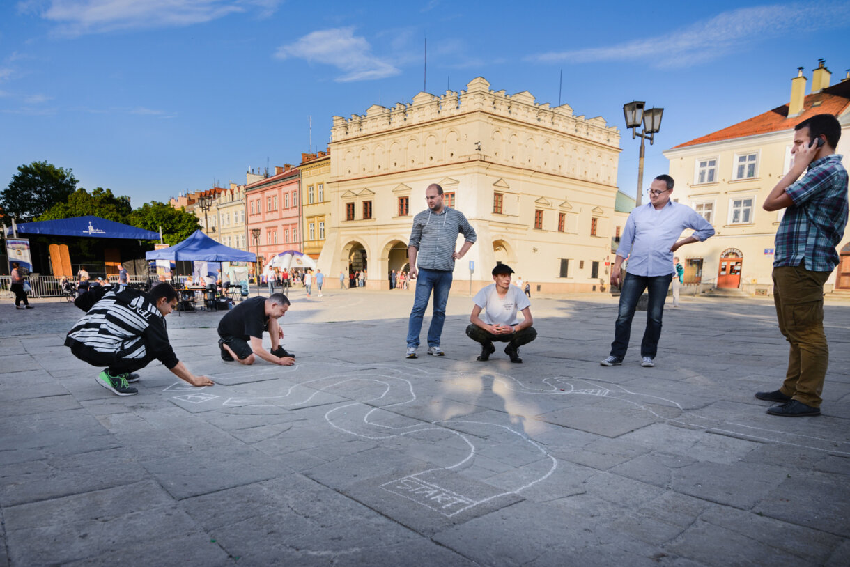 Ludzie grający w kapsle, w tle kamienica Orsettich