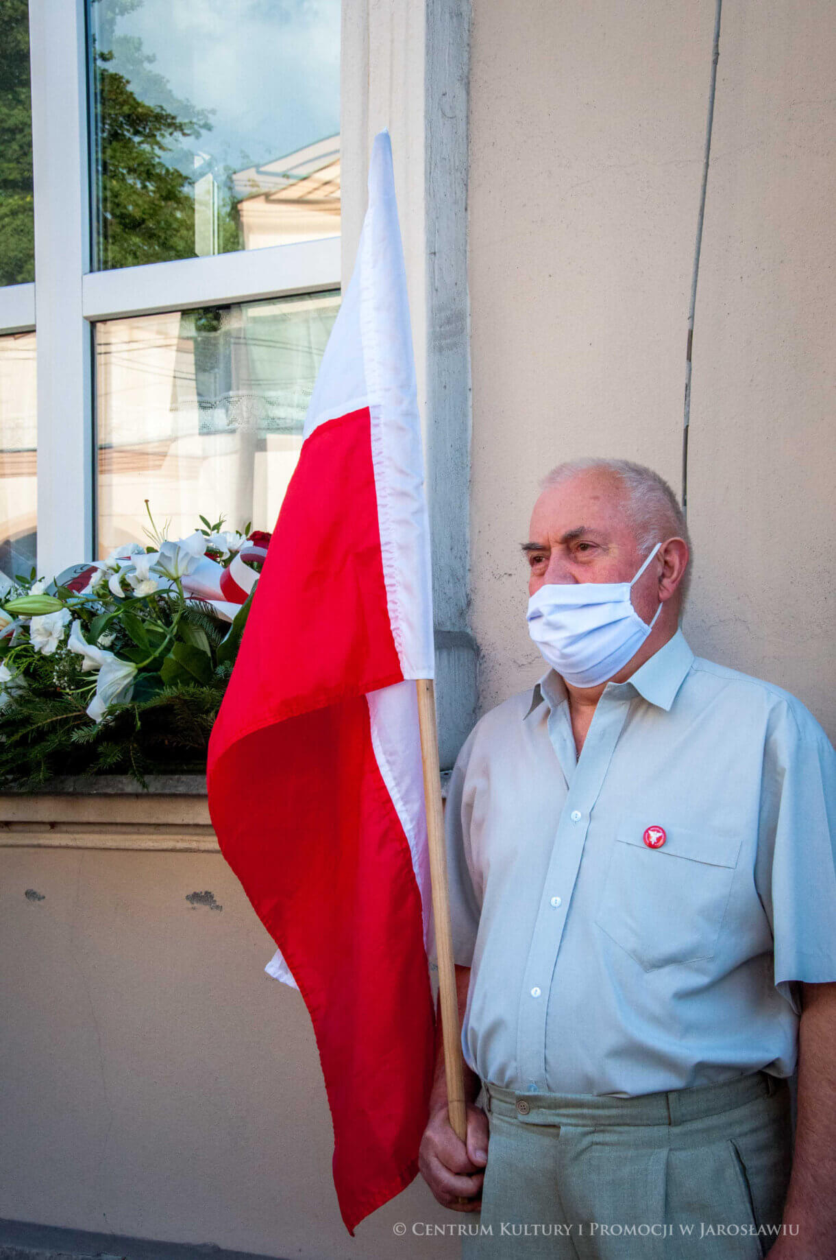 Uczestnik uroczystości trzymający flagę Polski