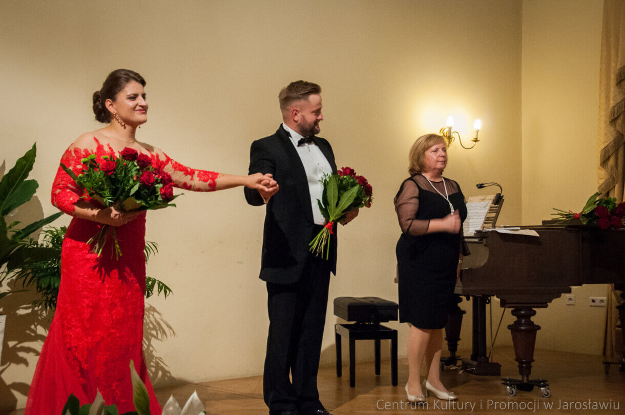 artyści na scenie na zakończeniu koncertu z kwiatami w rękach