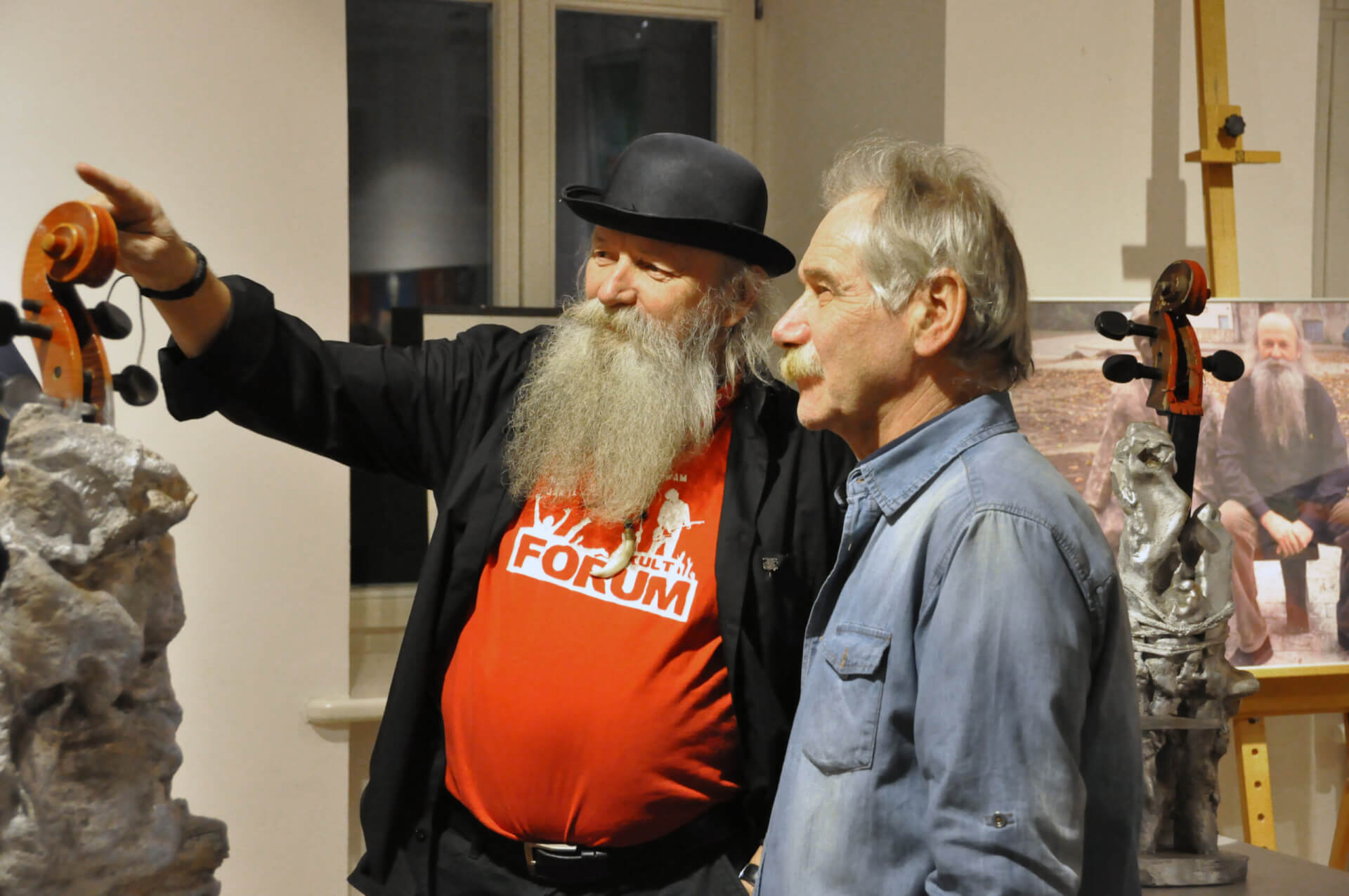 Henryk Cebula podczas wernisażu razem z kolegą oglądają prace artysty