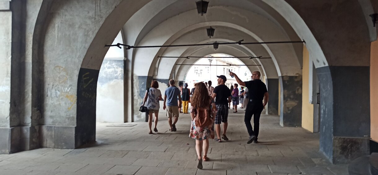 Grupa ludzi pod podcieniami jednej z jarosławskich kamienic