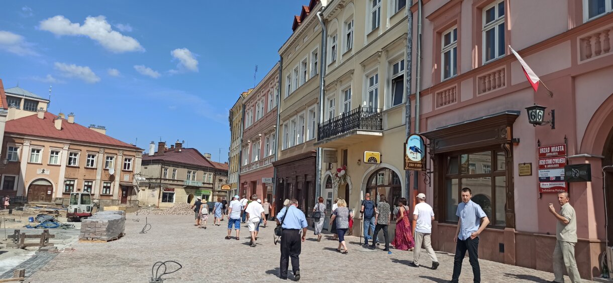grupa osób podczas zwiedzania miasta przed kamienicami na rynku