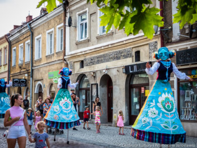 Spektakle na ulicy spektakl "Folkowe brzmienia" - postacie na szczudłach w folkowych strojach