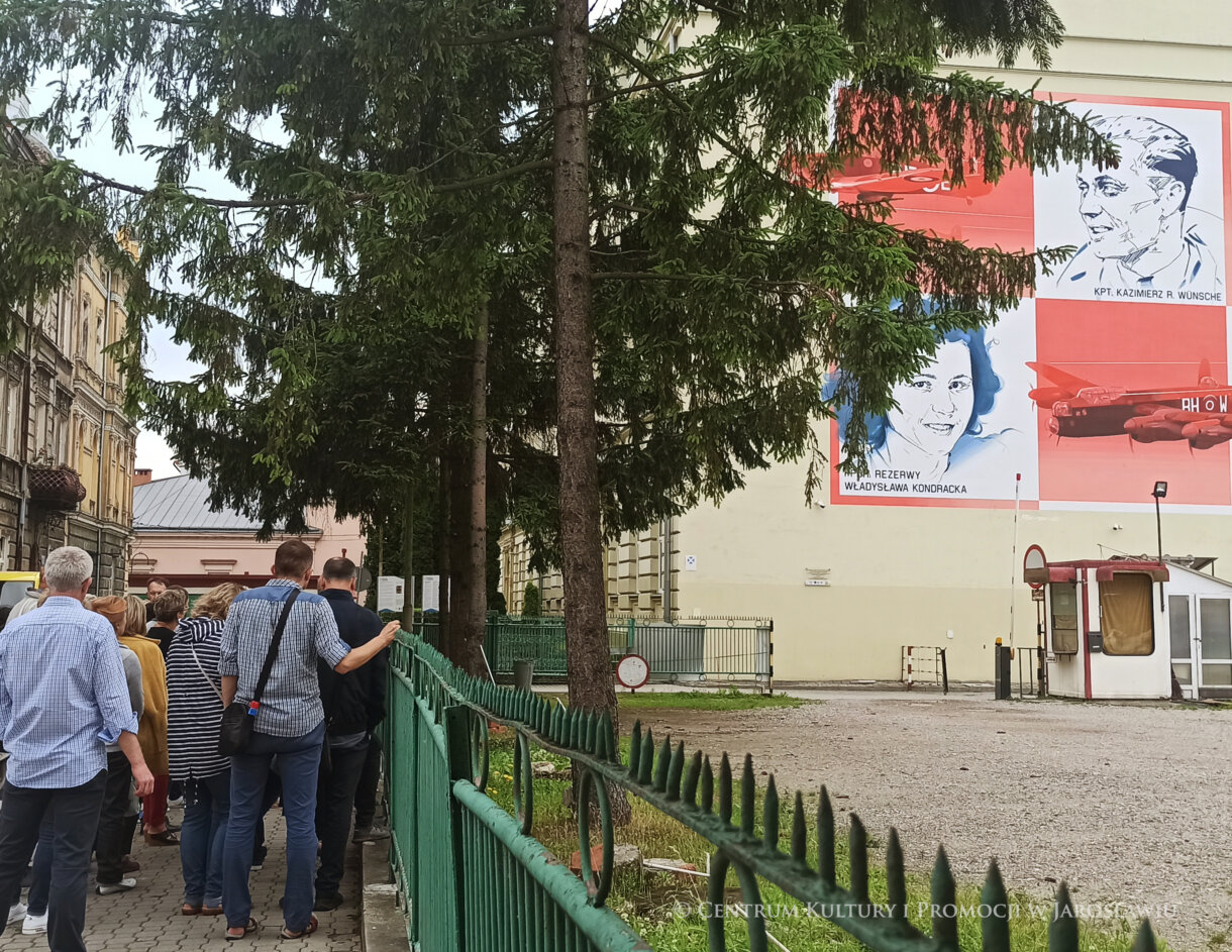 Grupa ludzi, z prawej mural pamięci lotników RAF
