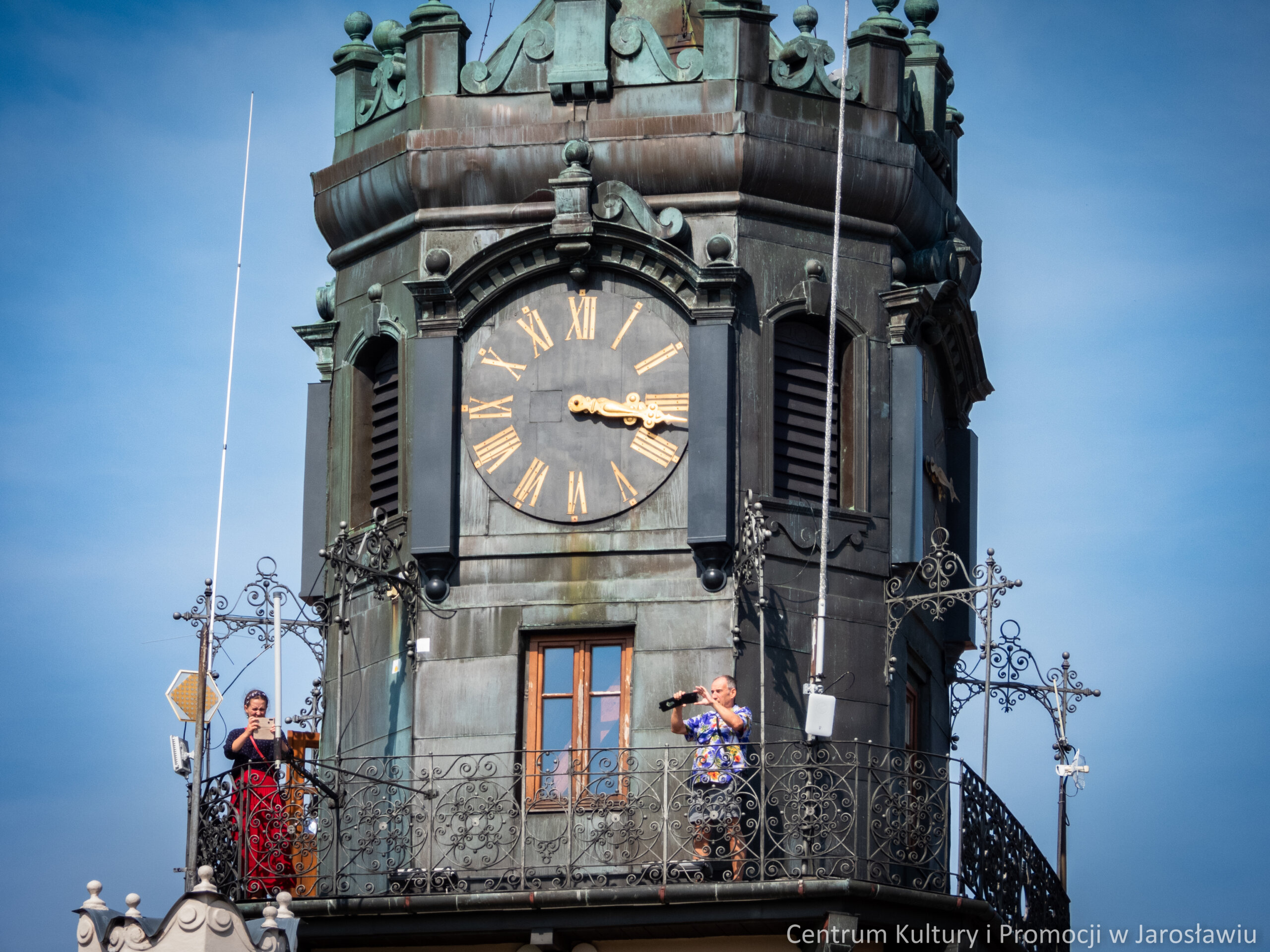 grupa osób zwiedzających miasta na wieży ratuszowej