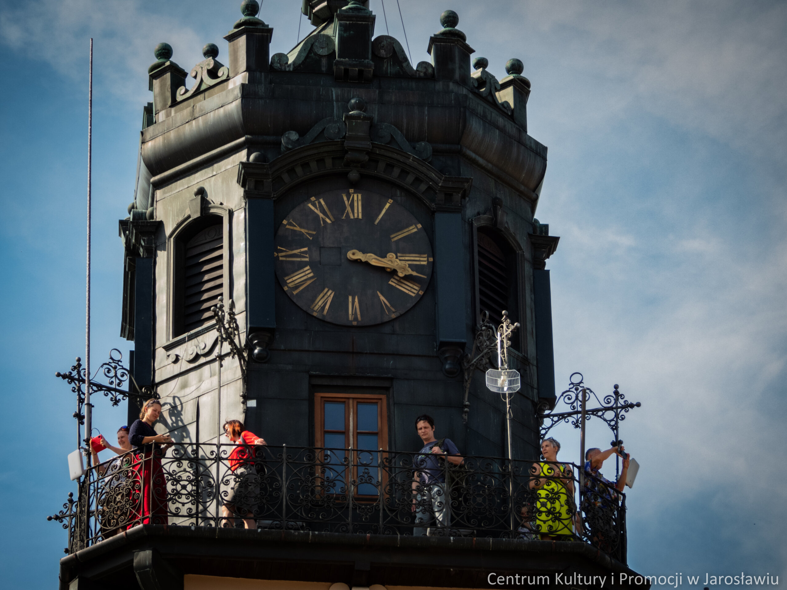 grupa osób zwiedzających miasta na wieży ratuszowej