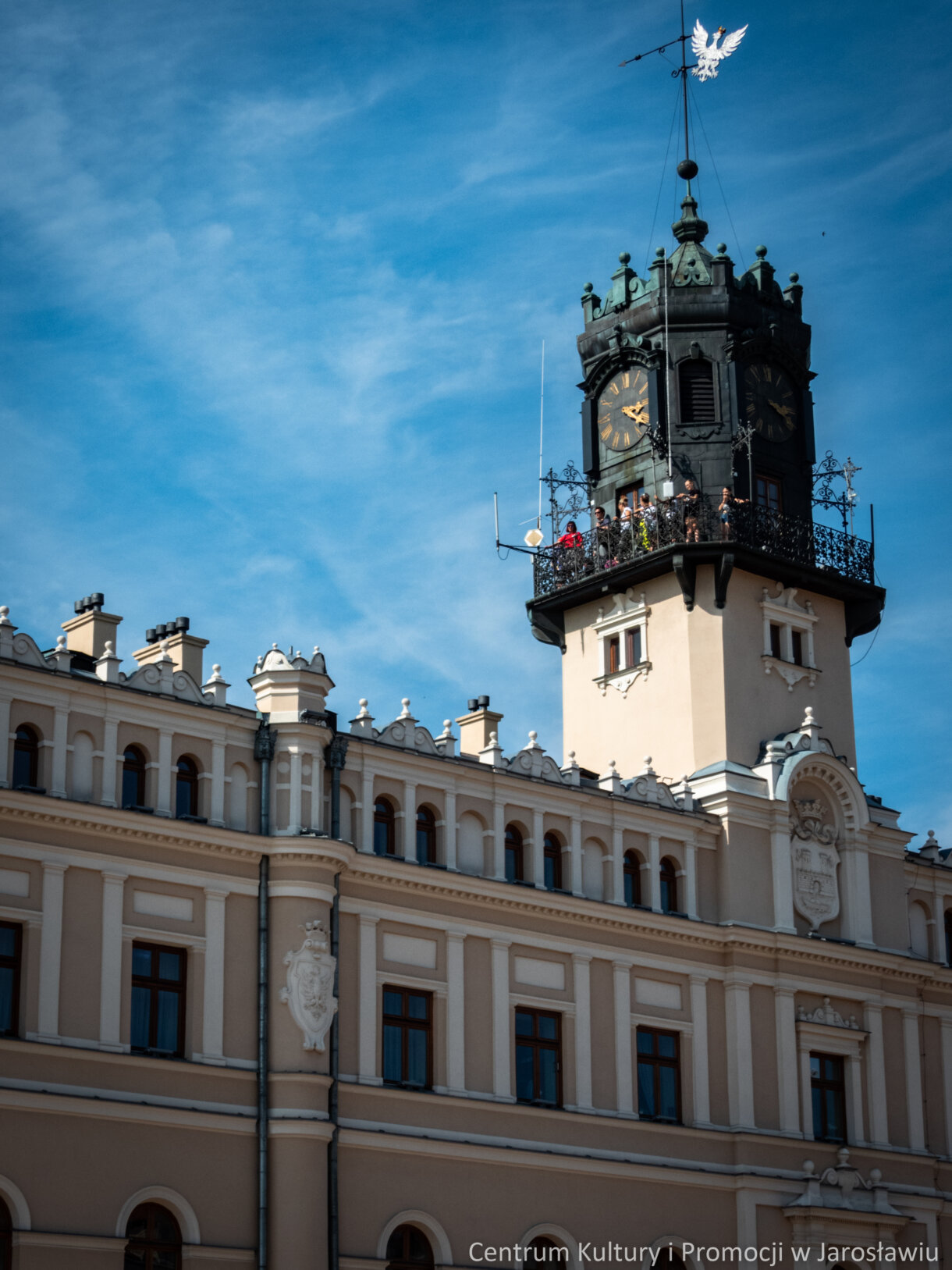 grupa osób zwiedzających miasta na wieży ratuszowej