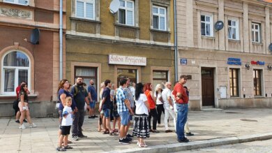 Za nami kolejny spacerek z cyklu Niedzielne spacerki po Jarosławiu z przewodnikiem! grupa osób podczas zwiedzania miasta przed kamienicami na rynku