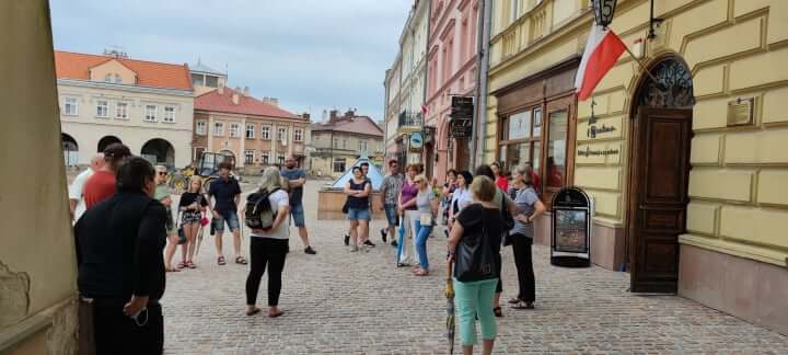 grupa osób podczas zwiedzania miasta przed kamienicami na rynku