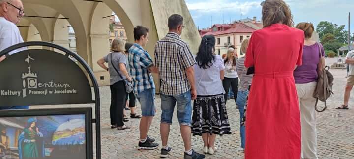 grupa osób podczas zwiedzania miasta przed kamienicami na rynku