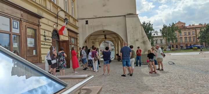 grupa osób podczas zwiedzania miasta przed kamienicami na rynku