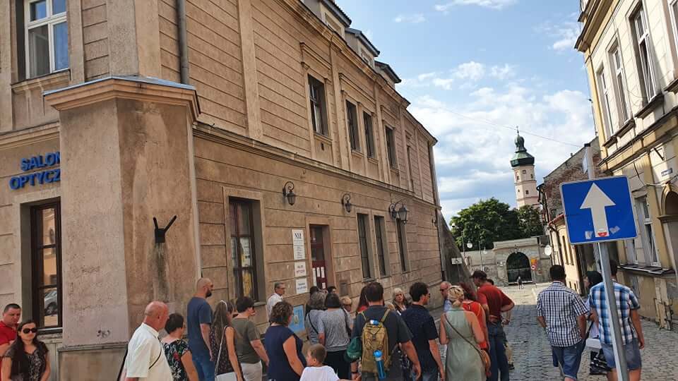 grupa osób podczas zwiedzania miasta przed kamienicami na rynku