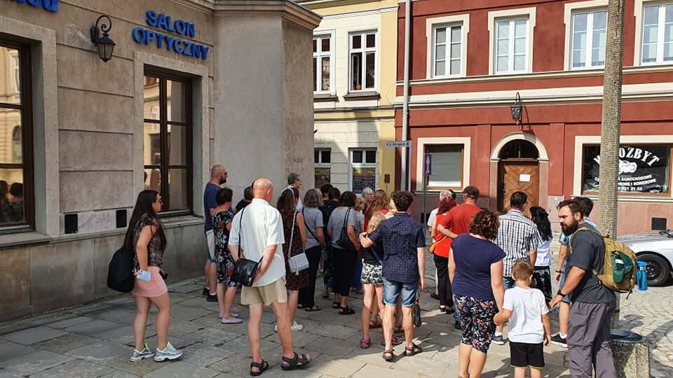 grupa osób podczas zwiedzania miasta przed kamienicami na rynku