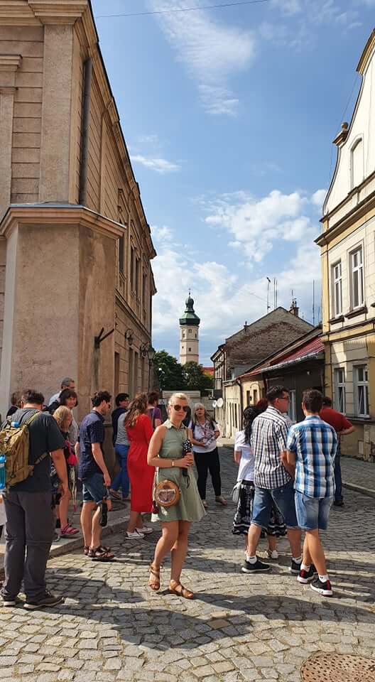 grupa osób podczas zwiedzania miasta przed kamienicami na rynku
