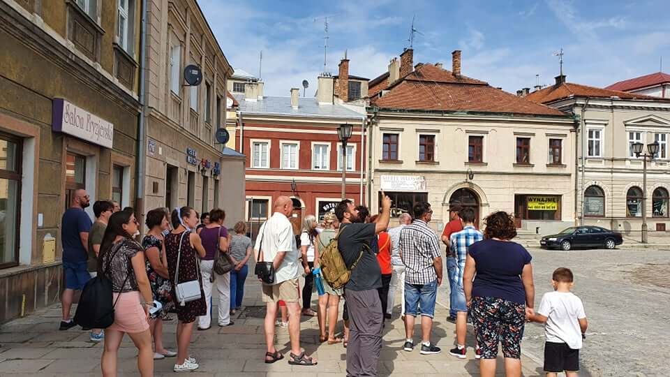 grupa osób podczas zwiedzania miasta przed kamienicami na rynku