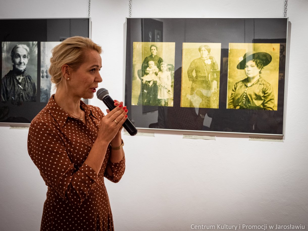 Bernadetta Korczewska kustosz galerii podczas otwarcia wystawy, w tle pamiątkowe fotografie