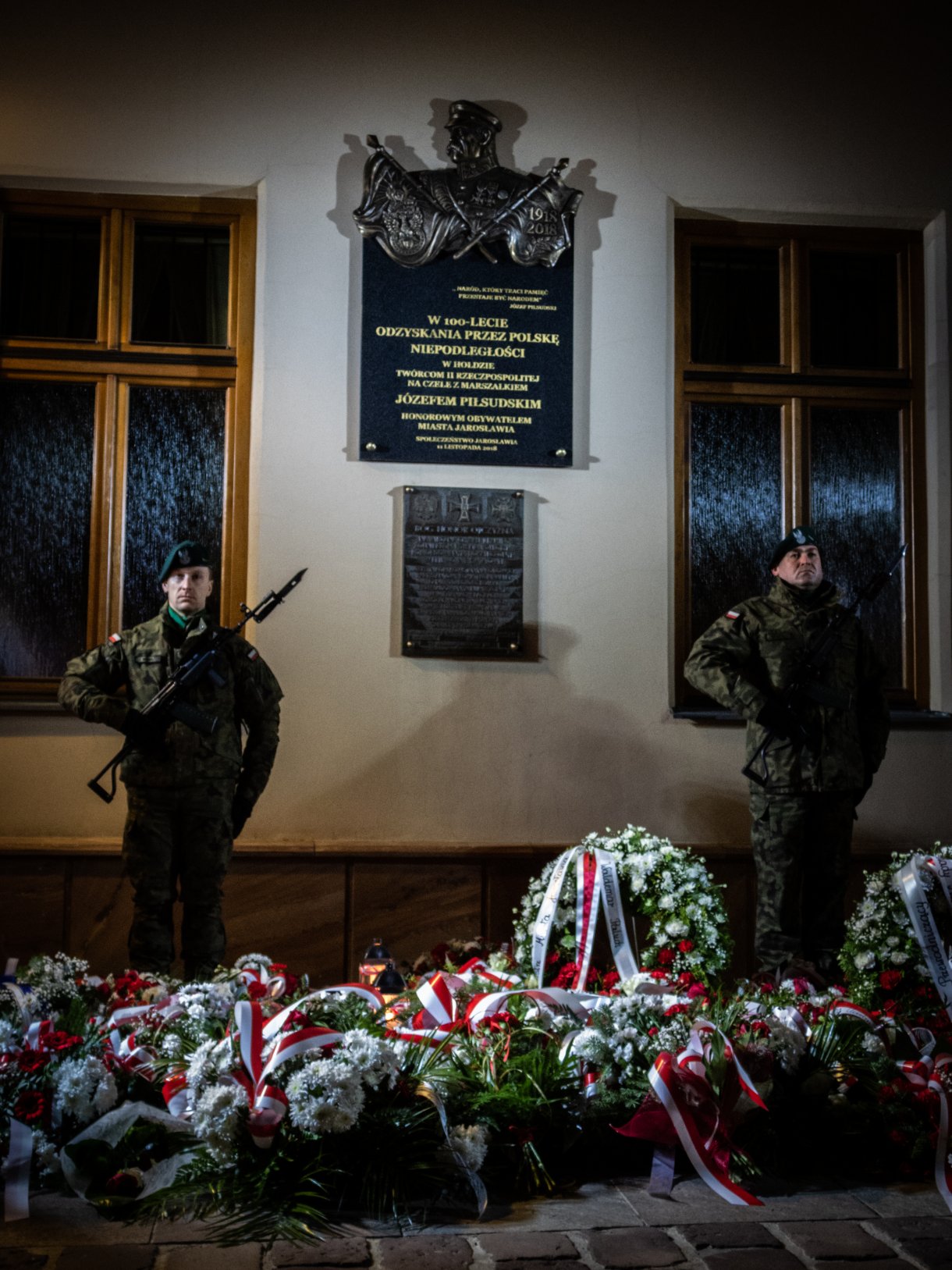 tablica pamiątkowa w asyście dwóch żołnierzy, poniżej kwiaty