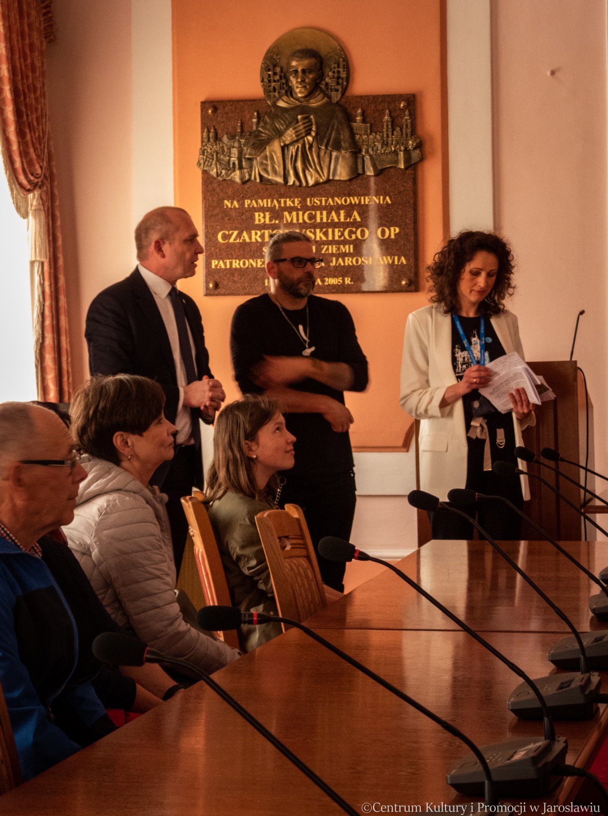 zwiedzanie Sali Narad, w tle zastępca burmistrza miasta, radny rady miasta oraz przewodnik po ratuszu