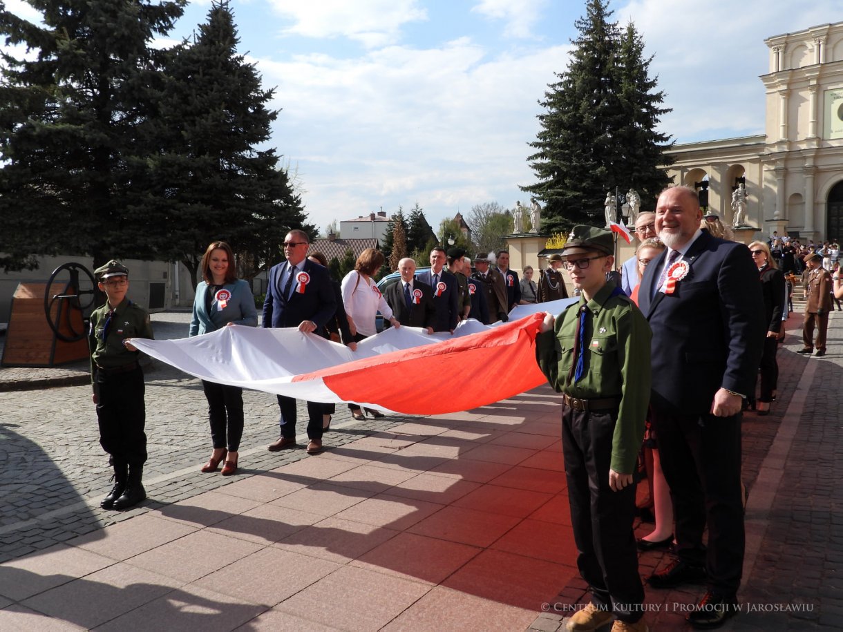 Początek maja to czas upamiętniający jedne z najważniejszych wydarzeń i symboli w naszej historii. Od 2004 roku w całej Polsce, 2 maja obchodzimy Dzień Flagi RP natomiast 3 maja przypada Święto Narodowe Trzeciego Maja. Dzień Flag RP to święto wprowadzone na mocy ustawy z 20 lutego 2004 r. Jarosławskie obchody Święta Flagi RP rozpoczęły się uroczystym przemarszem z placu ks. Piotra Skargi na jarosławski Rynek. Biało-czerwony korowód niosący 30-metrową flagę prowadzony był przez Orkiestrę Dętą „Laudate Dominum” oraz kompanię reprezentacyjna Wojska Polskiego. Po dotarciu na rynek, uroczyście podniesiono flagę na masz. Towarzyszył temu odegrany przez „Laudate Dominum” oraz odśpiewany przez żołnierzy i wszystkich zebranych Mazurek Dąbrowskiego. Okolicznościowe przemówienie wygłosił min. Burmistrz Miasta Jarosławia Waldemar Paluch, który podkreślał wagę symboli narodowych w tym szczególnym czasie, po czym miała miejsce defilada wojskowa. Na zakończenie obchodów rozdane zostały biało-czerwone flagi, wykonano wspólne pamiątkowe zdjęcie, a dzieci mogły wziąć udział w specjalnie dla nich przygotowanych animacjach i zabawach. Święto Narodowe Trzeciego Maja otworzył koncert Reprezentacyjnego Chóru Mieszanego „Jarosław”, który poprzedził mszę święto w intencji Ojczyzny, odprawioną w kościele p.w. NMP Królowej Polski. Po eucharystii udano się pod pomnik Konstytucji Trzeciego Maja gdzie w towarzystwie Mazurka Dąbrowskiego podniesiono flagę na maszt. Po okolicznościowych przemówieniach odczytana apel pamięci, następnie kompania honorowa Wojska Polskiego oddała salwę honorową. Później nastąpiło złożenie kwiatów pod Pomnikiem przez władze parlamentarzystów, władze wojewódzkie i samorządowe, służby i instytucje publiczne, organizacje pozarządowe oraz szkoły.
