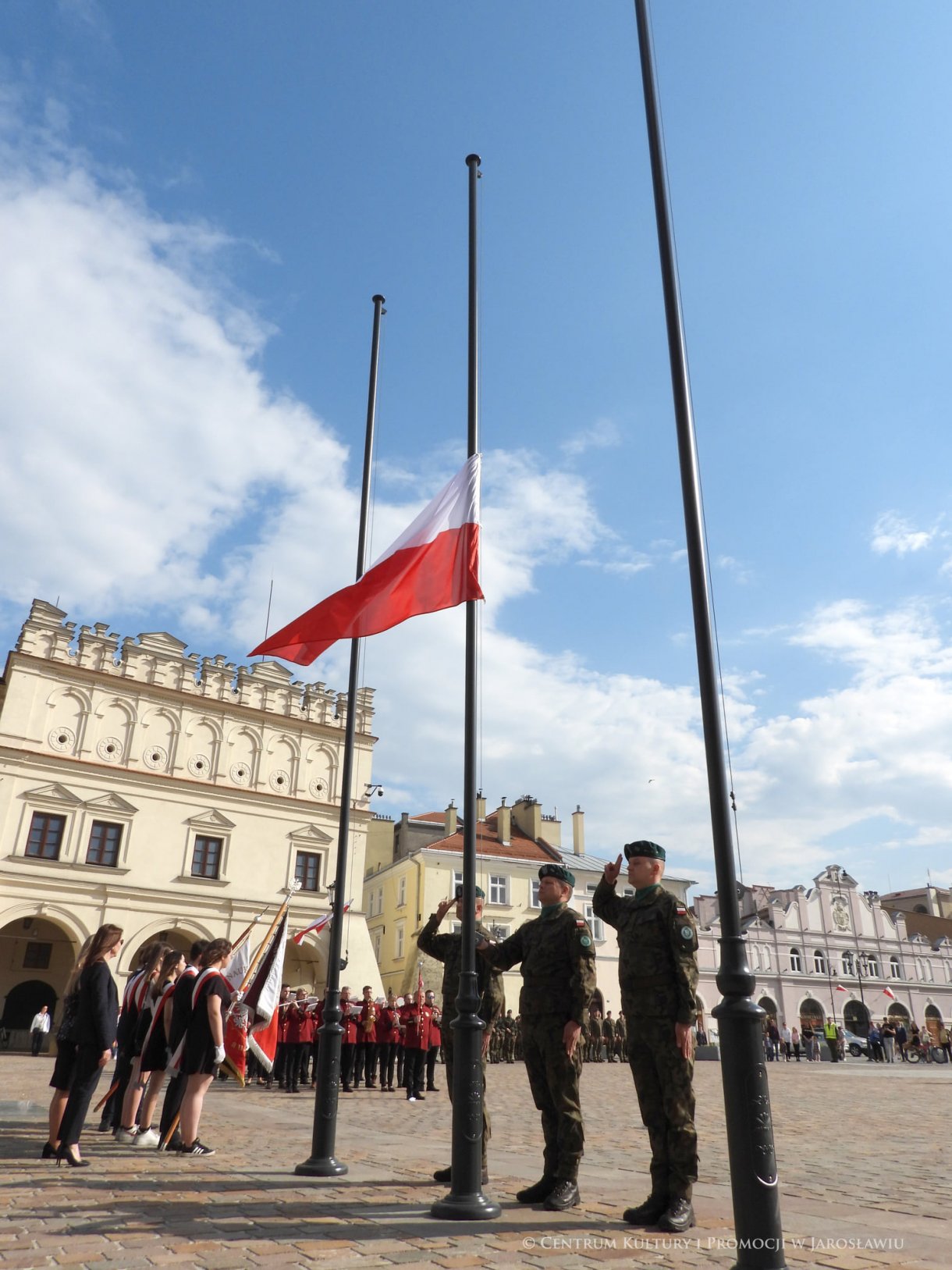 Początek maja to czas upamiętniający jedne z najważniejszych wydarzeń i symboli w naszej historii. Od 2004 roku w całej Polsce, 2 maja obchodzimy Dzień Flagi RP natomiast 3 maja przypada Święto Narodowe Trzeciego Maja. Dzień Flag RP to święto wprowadzone na mocy ustawy z 20 lutego 2004 r. Jarosławskie obchody Święta Flagi RP rozpoczęły się uroczystym przemarszem z placu ks. Piotra Skargi na jarosławski Rynek. Biało-czerwony korowód niosący 30-metrową flagę prowadzony był przez Orkiestrę Dętą „Laudate Dominum” oraz kompanię reprezentacyjna Wojska Polskiego. Po dotarciu na rynek, uroczyście podniesiono flagę na masz. Towarzyszył temu odegrany przez „Laudate Dominum” oraz odśpiewany przez żołnierzy i wszystkich zebranych Mazurek Dąbrowskiego. Okolicznościowe przemówienie wygłosił min. Burmistrz Miasta Jarosławia Waldemar Paluch, który podkreślał wagę symboli narodowych w tym szczególnym czasie, po czym miała miejsce defilada wojskowa. Na zakończenie obchodów rozdane zostały biało-czerwone flagi, wykonano wspólne pamiątkowe zdjęcie, a dzieci mogły wziąć udział w specjalnie dla nich przygotowanych animacjach i zabawach. Święto Narodowe Trzeciego Maja otworzył koncert Reprezentacyjnego Chóru Mieszanego „Jarosław”, który poprzedził mszę święto w intencji Ojczyzny, odprawioną w kościele p.w. NMP Królowej Polski. Po eucharystii udano się pod pomnik Konstytucji Trzeciego Maja gdzie w towarzystwie Mazurka Dąbrowskiego podniesiono flagę na maszt. Po okolicznościowych przemówieniach odczytana apel pamięci, następnie kompania honorowa Wojska Polskiego oddała salwę honorową. Później nastąpiło złożenie kwiatów pod Pomnikiem przez władze parlamentarzystów, władze wojewódzkie i samorządowe, służby i instytucje publiczne, organizacje pozarządowe oraz szkoły.