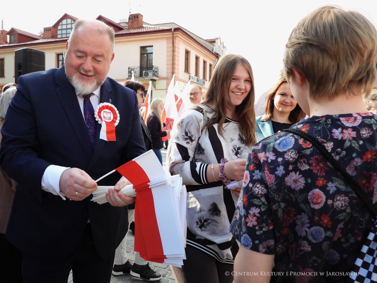 Początek maja to czas upamiętniający jedne z najważniejszych wydarzeń i symboli w naszej historii. Od 2004 roku w całej Polsce, 2 maja obchodzimy Dzień Flagi RP natomiast 3 maja przypada Święto Narodowe Trzeciego Maja. Dzień Flag RP to święto wprowadzone na mocy ustawy z 20 lutego 2004 r. Jarosławskie obchody Święta Flagi RP rozpoczęły się uroczystym przemarszem z placu ks. Piotra Skargi na jarosławski Rynek. Biało-czerwony korowód niosący 30-metrową flagę prowadzony był przez Orkiestrę Dętą „Laudate Dominum” oraz kompanię reprezentacyjna Wojska Polskiego. Po dotarciu na rynek, uroczyście podniesiono flagę na masz. Towarzyszył temu odegrany przez „Laudate Dominum” oraz odśpiewany przez żołnierzy i wszystkich zebranych Mazurek Dąbrowskiego. Okolicznościowe przemówienie wygłosił min. Burmistrz Miasta Jarosławia Waldemar Paluch, który podkreślał wagę symboli narodowych w tym szczególnym czasie, po czym miała miejsce defilada wojskowa. Na zakończenie obchodów rozdane zostały biało-czerwone flagi, wykonano wspólne pamiątkowe zdjęcie, a dzieci mogły wziąć udział w specjalnie dla nich przygotowanych animacjach i zabawach. Święto Narodowe Trzeciego Maja otworzył koncert Reprezentacyjnego Chóru Mieszanego „Jarosław”, który poprzedził mszę święto w intencji Ojczyzny, odprawioną w kościele p.w. NMP Królowej Polski. Po eucharystii udano się pod pomnik Konstytucji Trzeciego Maja gdzie w towarzystwie Mazurka Dąbrowskiego podniesiono flagę na maszt. Po okolicznościowych przemówieniach odczytana apel pamięci, następnie kompania honorowa Wojska Polskiego oddała salwę honorową. Później nastąpiło złożenie kwiatów pod Pomnikiem przez władze parlamentarzystów, władze wojewódzkie i samorządowe, służby i instytucje publiczne, organizacje pozarządowe oraz szkoły.