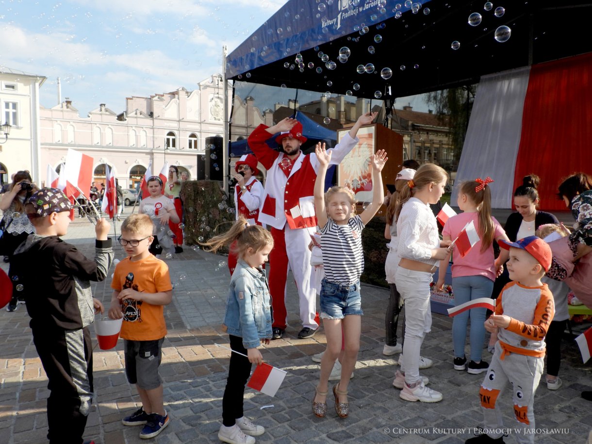 Początek maja to czas upamiętniający jedne z najważniejszych wydarzeń i symboli w naszej historii. Od 2004 roku w całej Polsce, 2 maja obchodzimy Dzień Flagi RP natomiast 3 maja przypada Święto Narodowe Trzeciego Maja. Dzień Flag RP to święto wprowadzone na mocy ustawy z 20 lutego 2004 r. Jarosławskie obchody Święta Flagi RP rozpoczęły się uroczystym przemarszem z placu ks. Piotra Skargi na jarosławski Rynek. Biało-czerwony korowód niosący 30-metrową flagę prowadzony był przez Orkiestrę Dętą „Laudate Dominum” oraz kompanię reprezentacyjna Wojska Polskiego. Po dotarciu na rynek, uroczyście podniesiono flagę na masz. Towarzyszył temu odegrany przez „Laudate Dominum” oraz odśpiewany przez żołnierzy i wszystkich zebranych Mazurek Dąbrowskiego. Okolicznościowe przemówienie wygłosił min. Burmistrz Miasta Jarosławia Waldemar Paluch, który podkreślał wagę symboli narodowych w tym szczególnym czasie, po czym miała miejsce defilada wojskowa. Na zakończenie obchodów rozdane zostały biało-czerwone flagi, wykonano wspólne pamiątkowe zdjęcie, a dzieci mogły wziąć udział w specjalnie dla nich przygotowanych animacjach i zabawach. Święto Narodowe Trzeciego Maja otworzył koncert Reprezentacyjnego Chóru Mieszanego „Jarosław”, który poprzedził mszę święto w intencji Ojczyzny, odprawioną w kościele p.w. NMP Królowej Polski. Po eucharystii udano się pod pomnik Konstytucji Trzeciego Maja gdzie w towarzystwie Mazurka Dąbrowskiego podniesiono flagę na maszt. Po okolicznościowych przemówieniach odczytana apel pamięci, następnie kompania honorowa Wojska Polskiego oddała salwę honorową. Później nastąpiło złożenie kwiatów pod Pomnikiem przez władze parlamentarzystów, władze wojewódzkie i samorządowe, służby i instytucje publiczne, organizacje pozarządowe oraz szkoły.