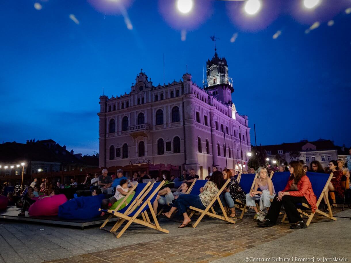 widzowie oglądający kino pod gwiazdami w tle ratusz