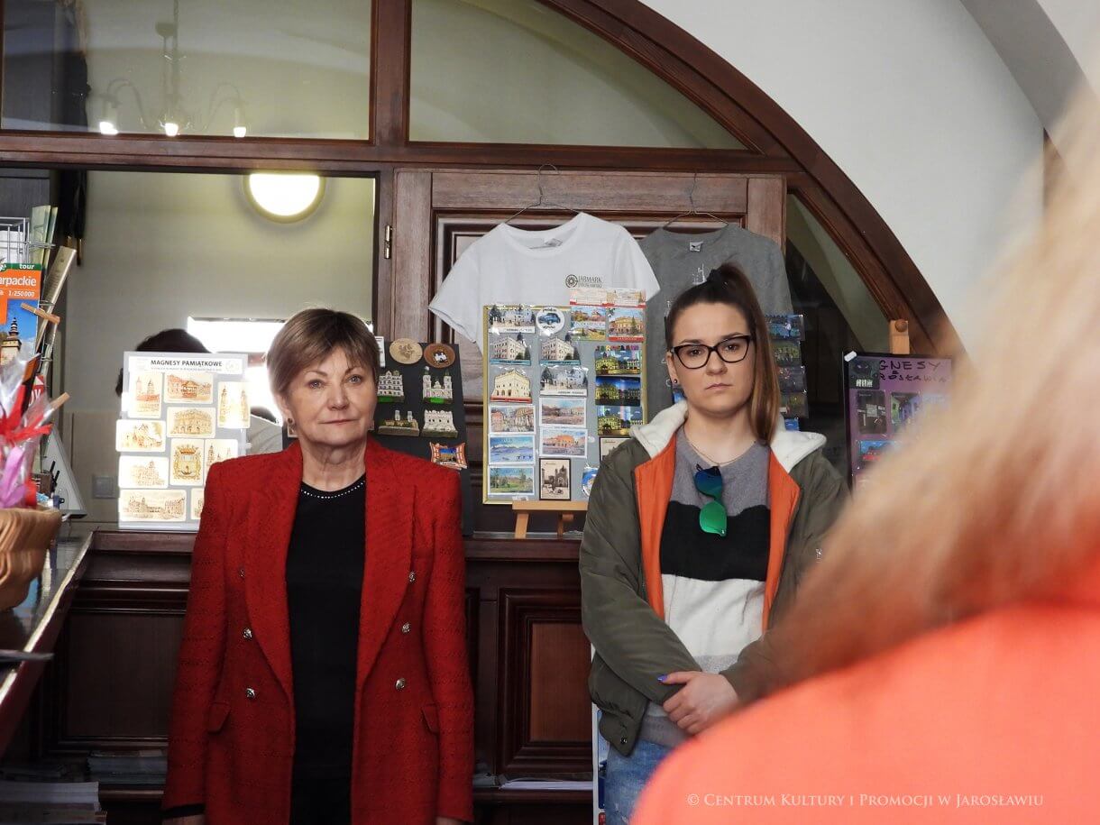 Dwie kobiety Centrum Informacji Turystyczno-Kulturalnej, z prawej fragment kobiety w czerwonym ubraniu