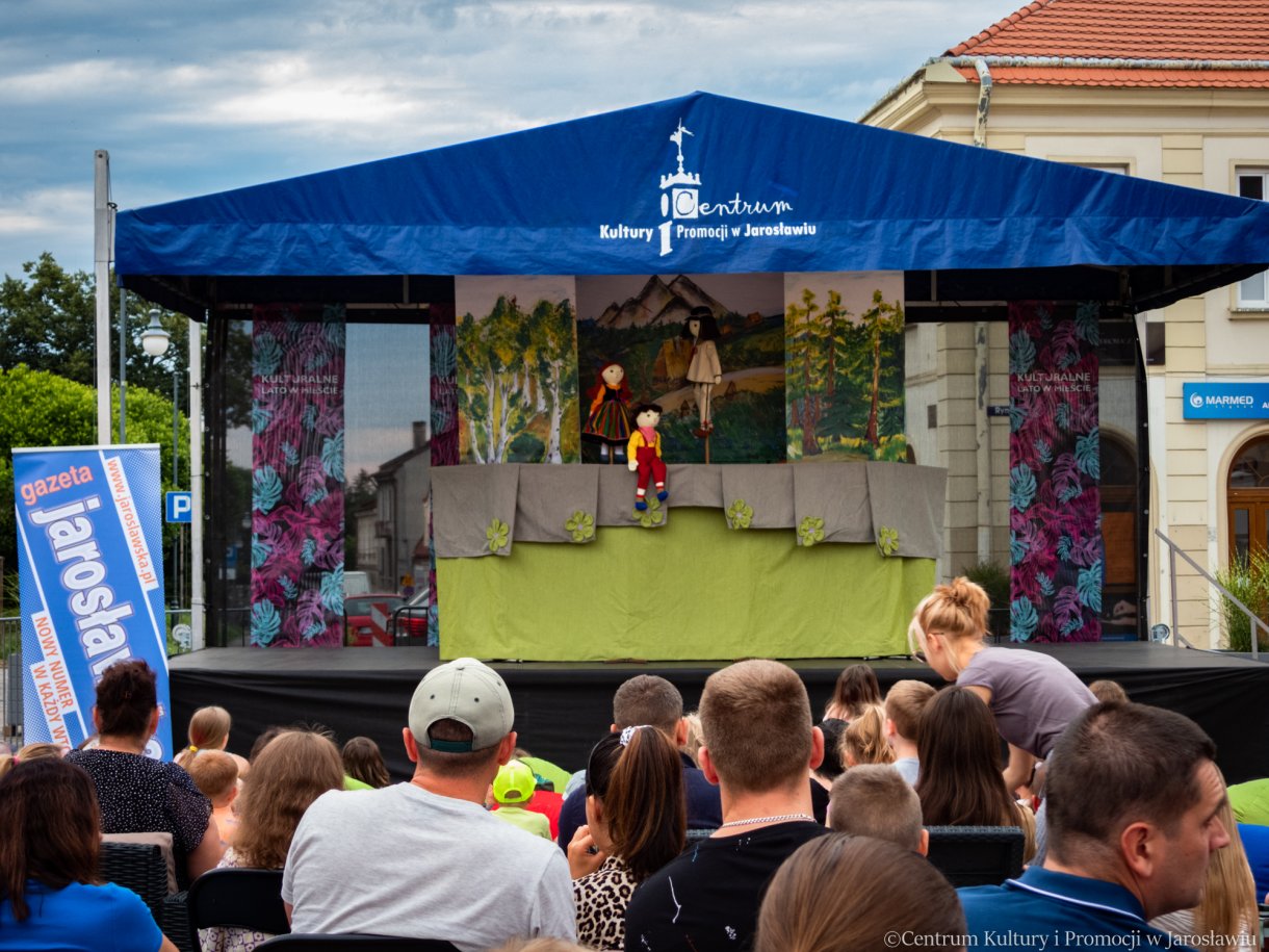 spojrzenie na scenę z teatrzykiem z oddali, na pierwszym planie publiczność w tle scena z teatrzykiem