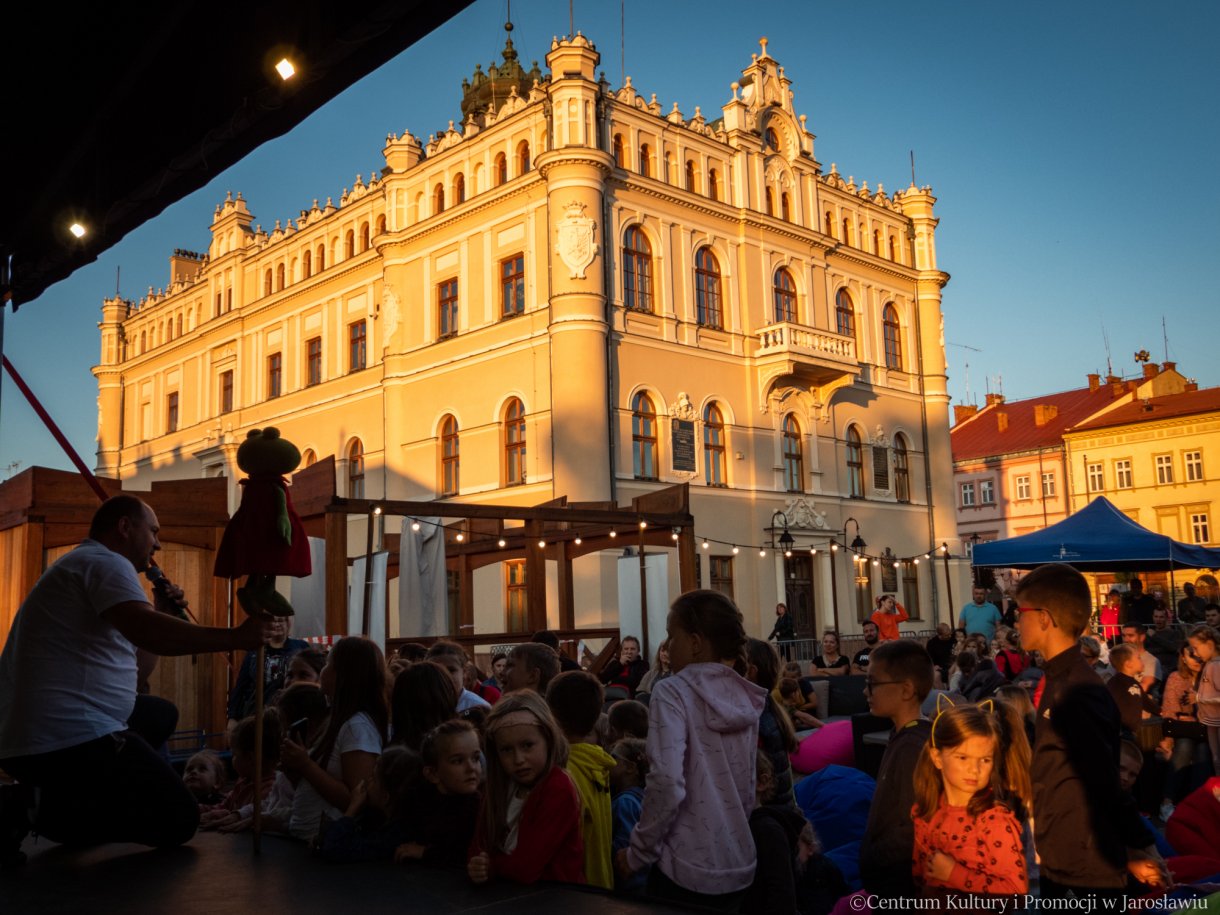 dzieci podczas oglądania z bliska kukiełek w tle ratusz