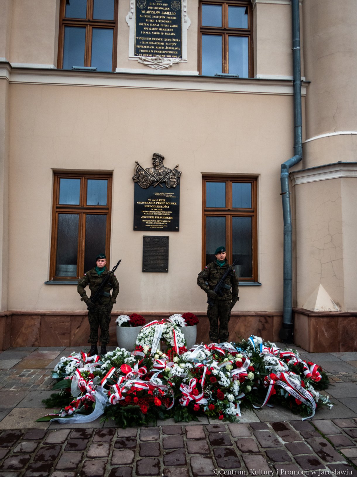 pamiątkowe wiązanki kwiatów złożone pod tablicą umieszczoną na Ratuszu podczas obchodów 11 listopada